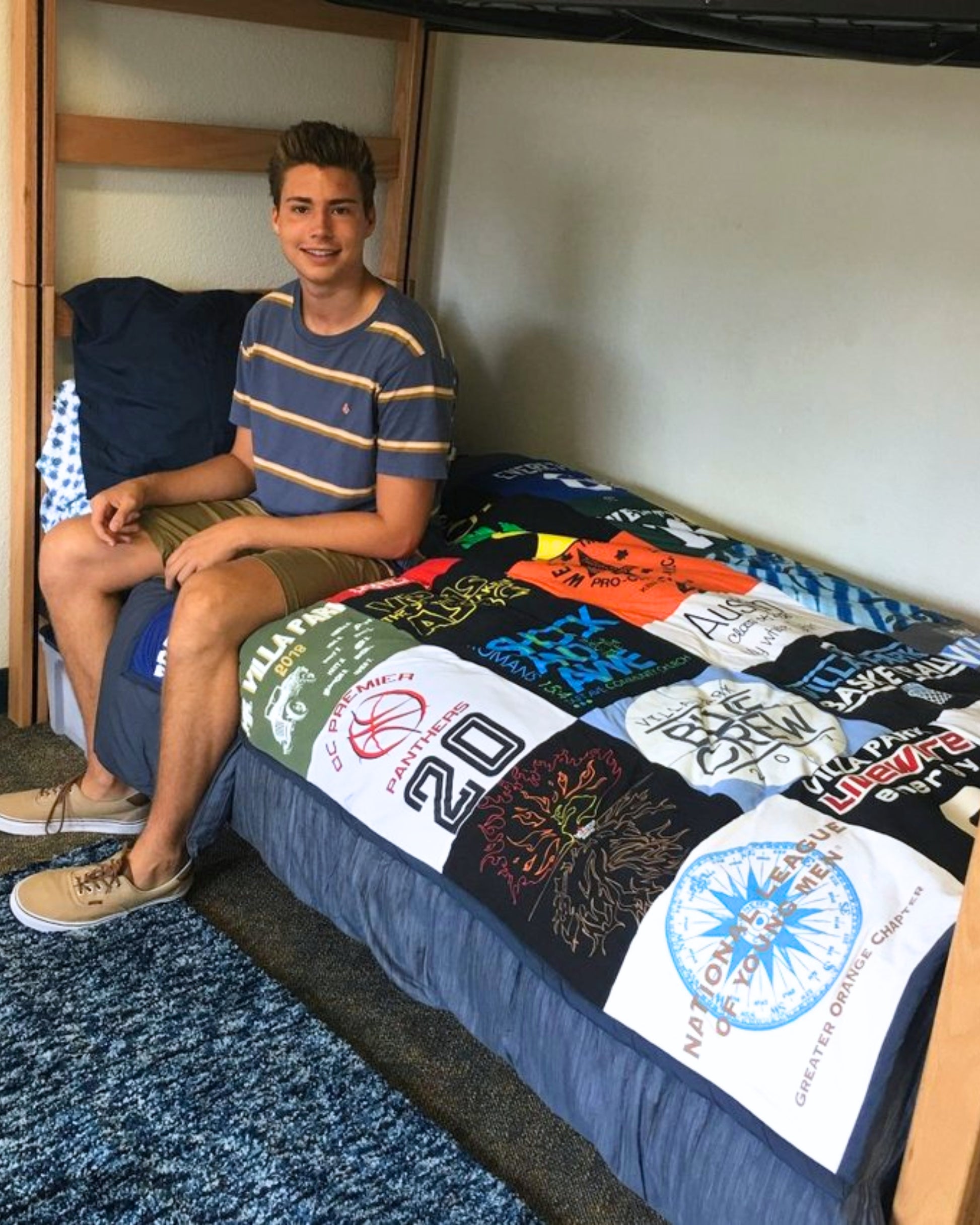 boy sitting on college dorm bed with t-shirt quilt