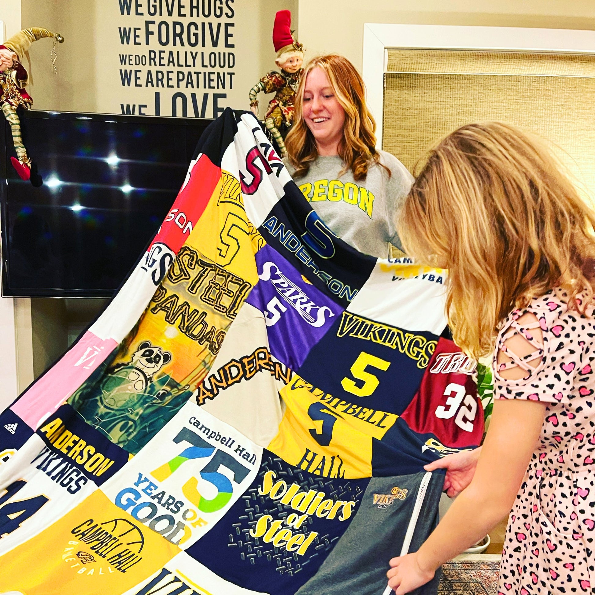 two women holding a memory blanket made of t-shirts